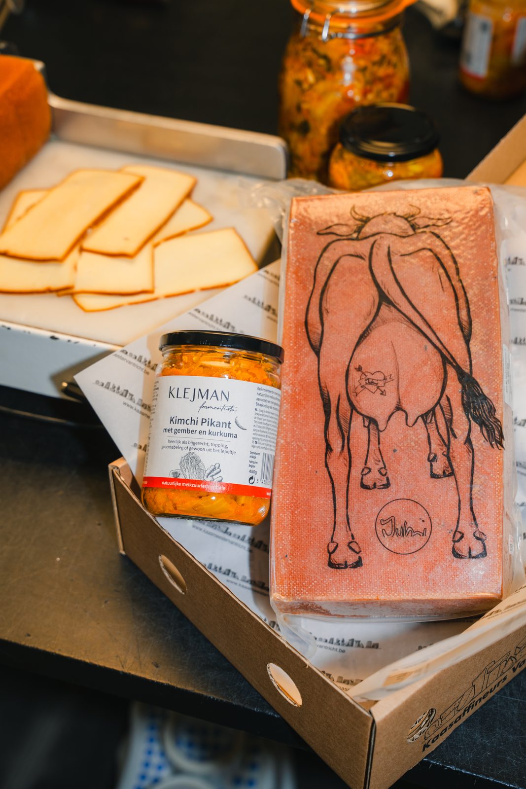Een bokaal kimchi van Klejman Fermentista naast een blok raclette en plakjes gerookte raclette van Van Tricht