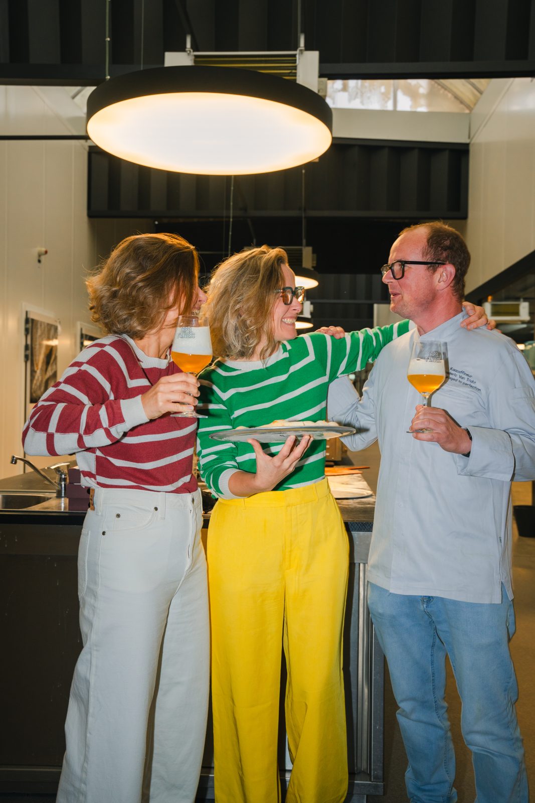 De zusjes Klejman en Frederic Van Tricht klinken met een glas bier en een pizza