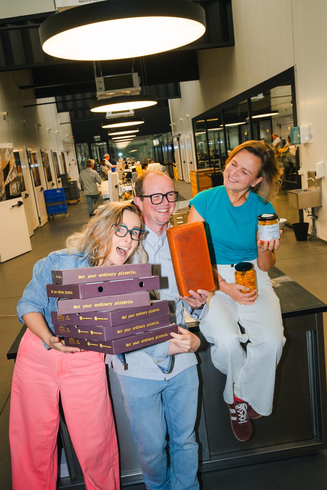 De zusjes Klejman en Frederic Van Tricht met een stapel Otomat-pizzadozen, een blok raclette en bokalen kimchi
