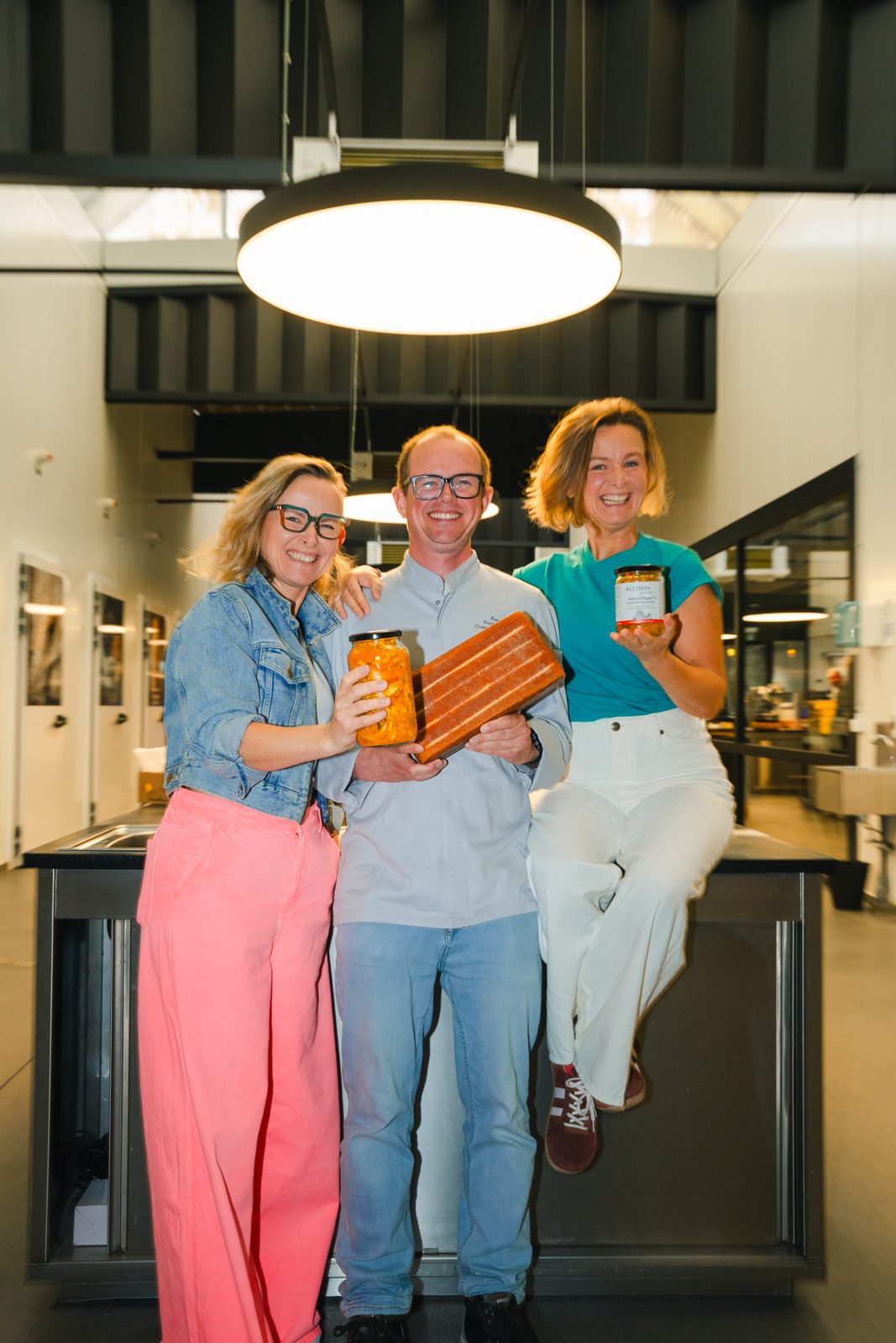 Marta en Joanna Klejman met kaasaffineur Frederic Van Tricht, met een bokaal kimchi en een blok raclette