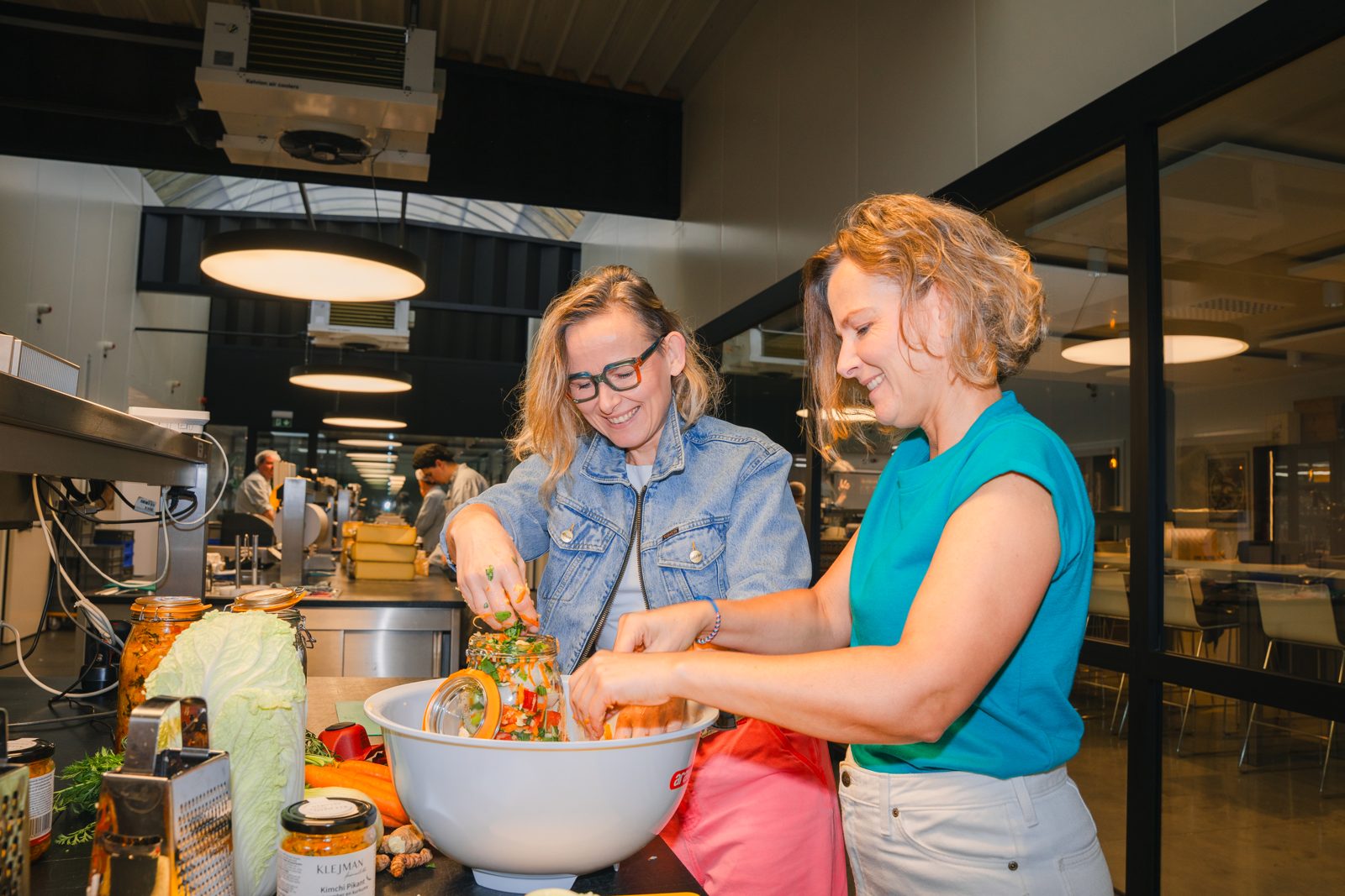 De zusjes Klejman vullen samen een bokaal met kimchi